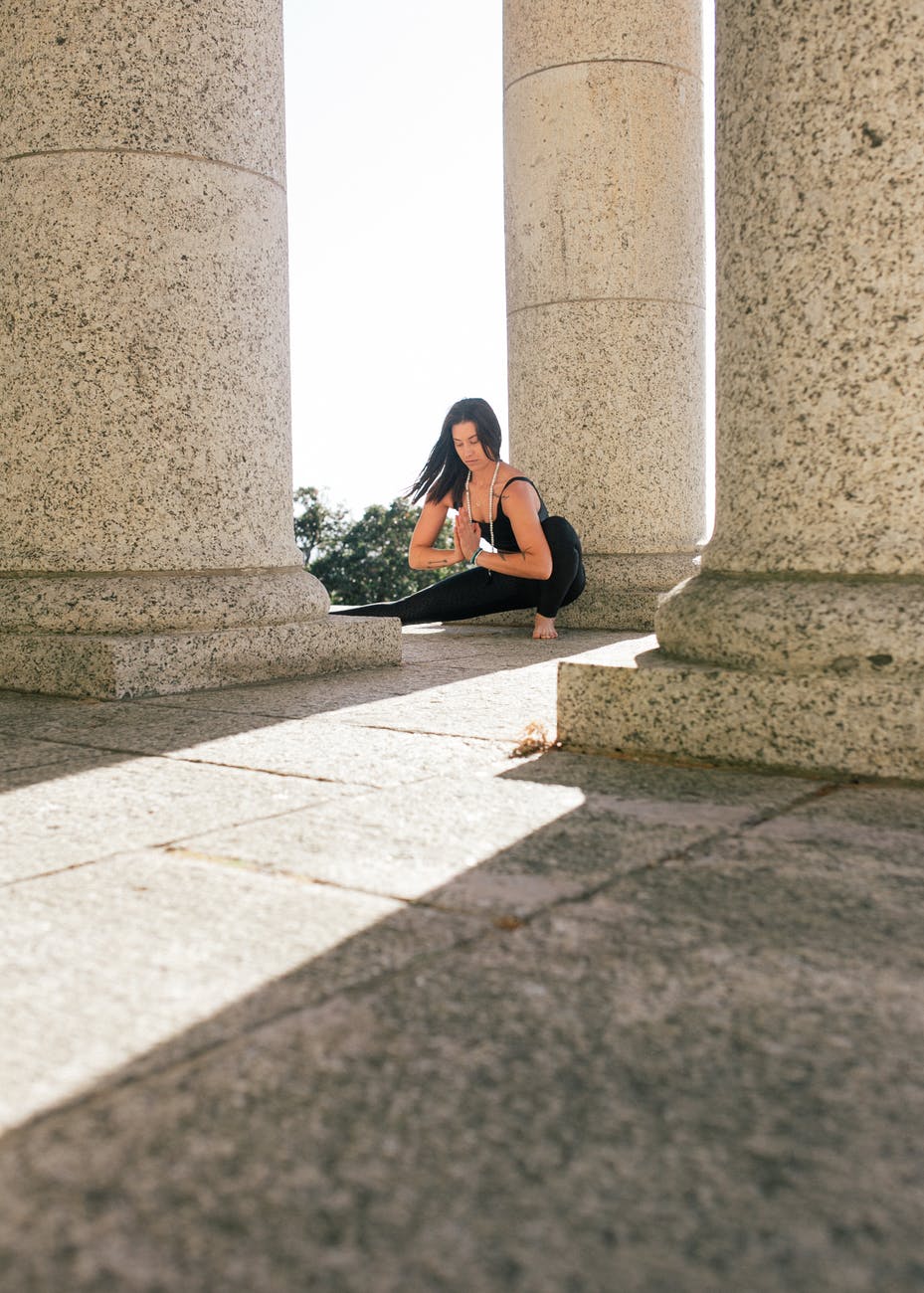 woman in black tank top and black pants practicing yoga